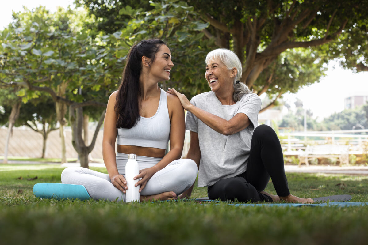 duas mulheres de idades diferentes sorrindo ao fazer exercícios ao ar livre.